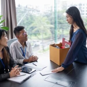A high performer tendering her resignation to the management and carrying a box with her things