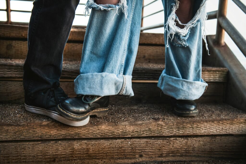 How to be a leader without a title without stepping on coworkers’ toes, close‑up of one person accidentally stepping on another’s boot on wooden stairs.