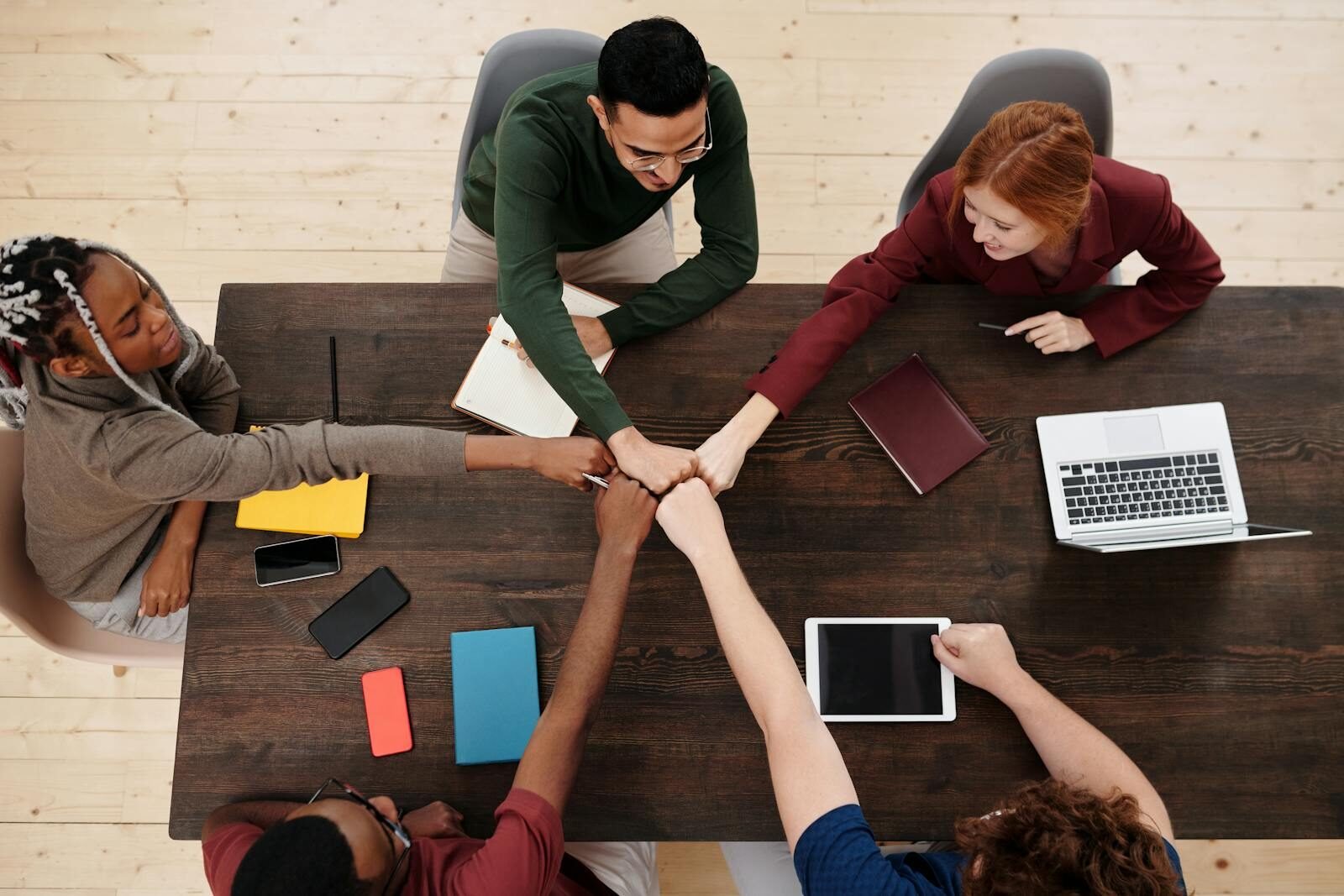 group of people in a business meeting, showing teamwork with technology on a wooden table. they are a highly productive teams