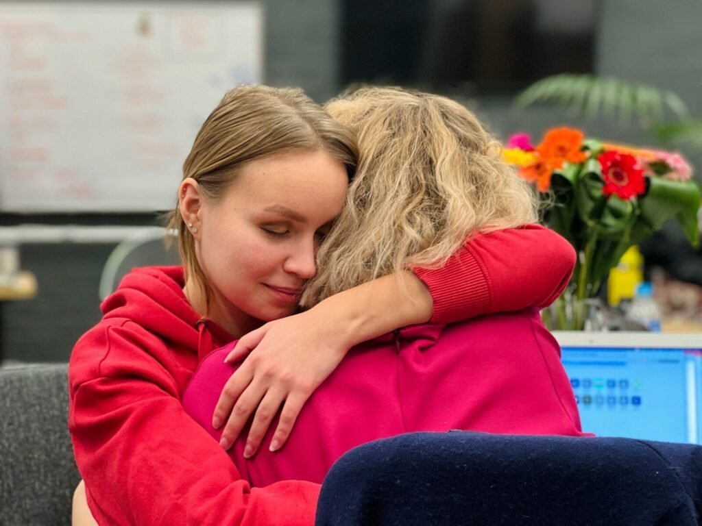 The ROI of Kindness: What AI Cannot Replace 3 two colleagues embracing at work showing human connection as a competitive advantage over AI