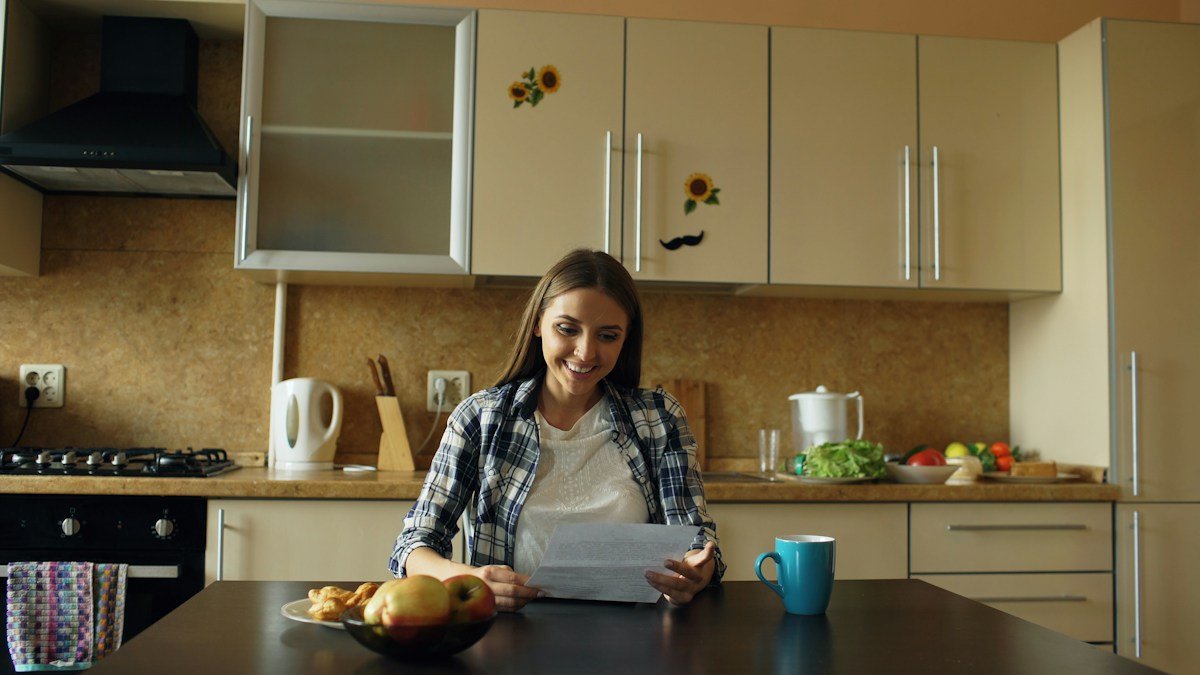 Woman at the kitchen table reading paperwork, the weekly admin behind household management